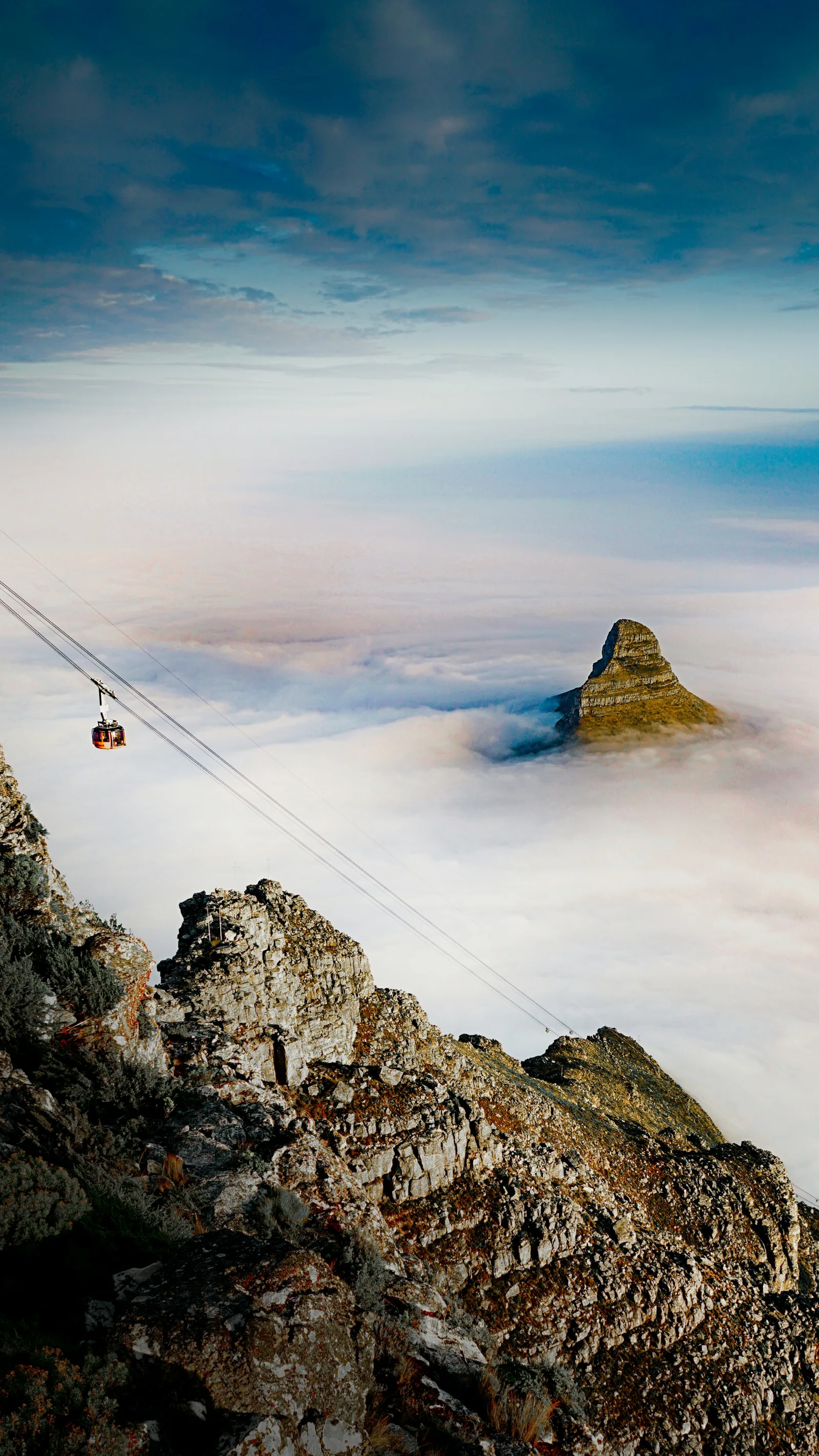 Morning light on Lion’s Head above low clouds, viewed from Table Mountain in Cape Town.